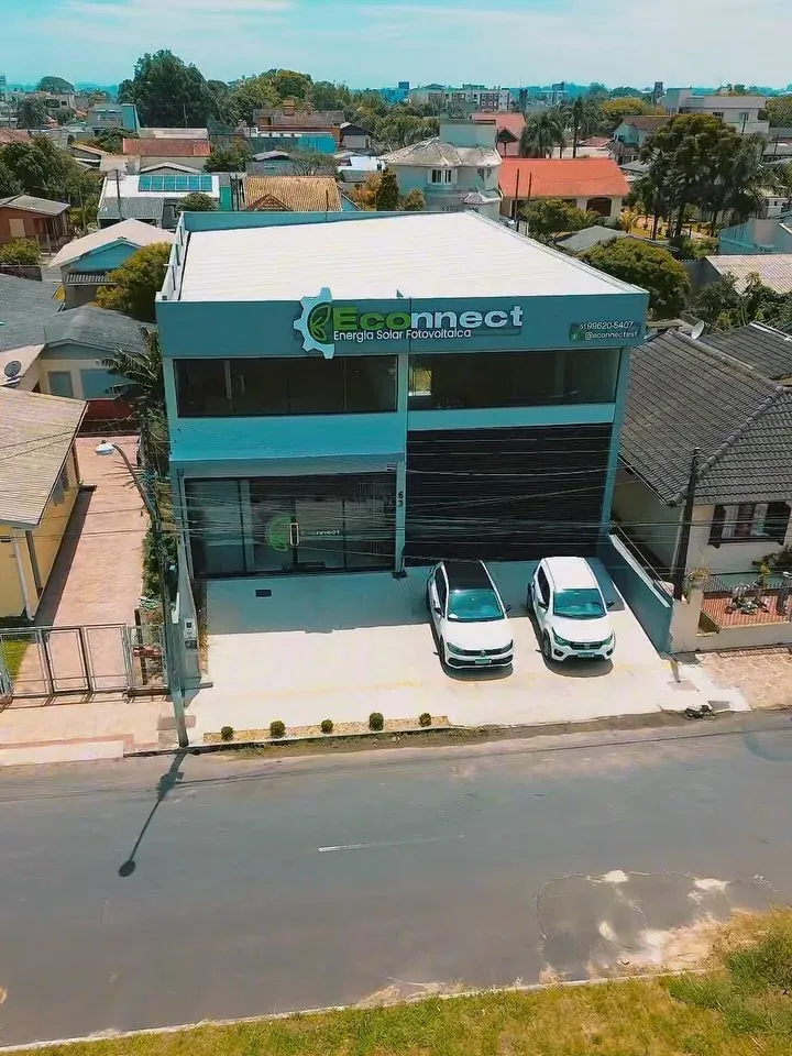 Fachada da sede da Econnect em Osório, com o letreiro da empresa e dois carros estacionados na frente.